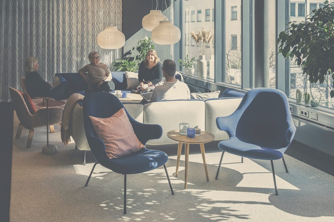 Fyra personer sitter och samtalar i en soffgrupp på ett kontor.